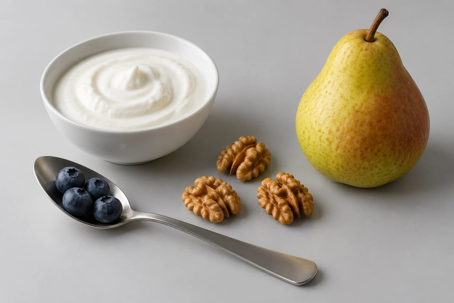 Yogurt, a pear, walnuts and blueberries photographed in a studio
